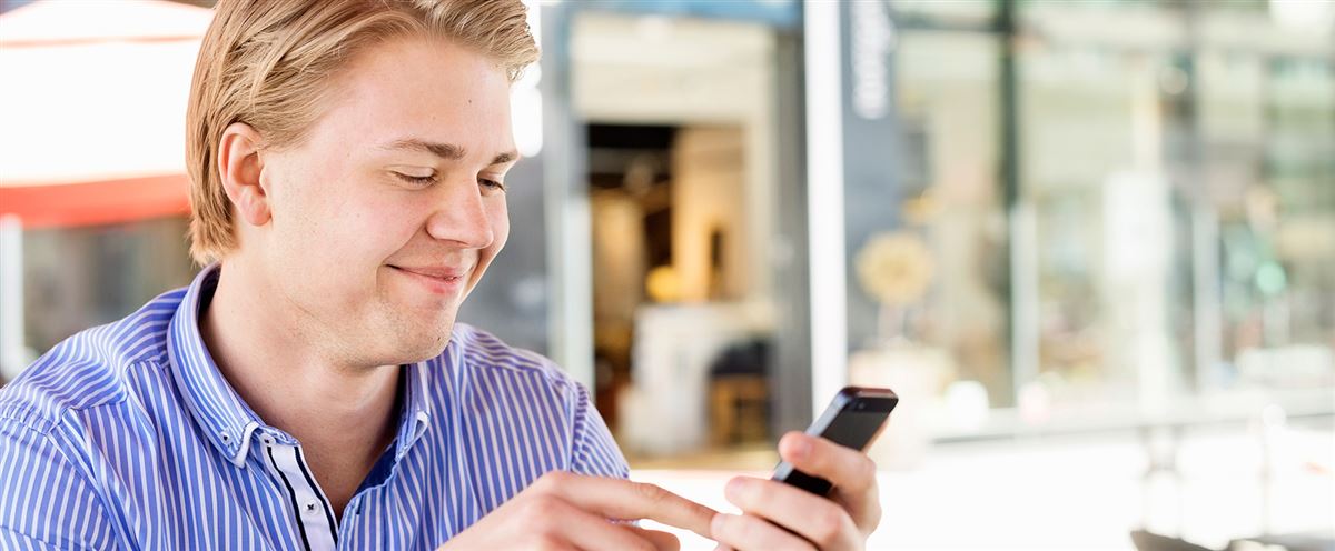 Glad kille tittar på mobilen
