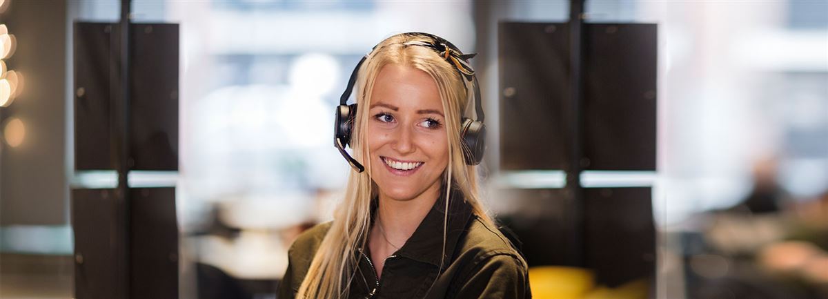 A woman is sitting at a desk, she is answering the phone using a headset.