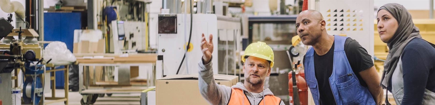 Two men and one woman are discussing a matter on the production floor. 