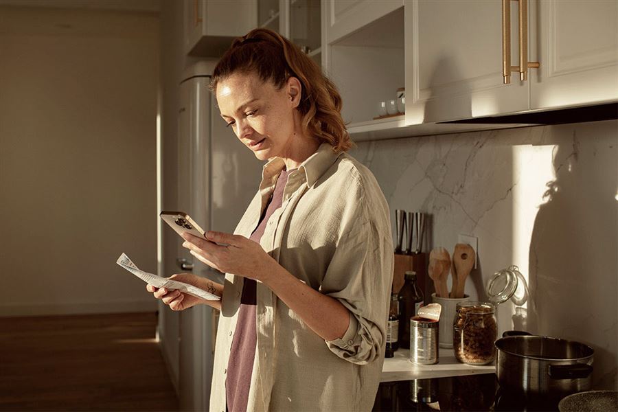 Woman with phone in the kitchen.