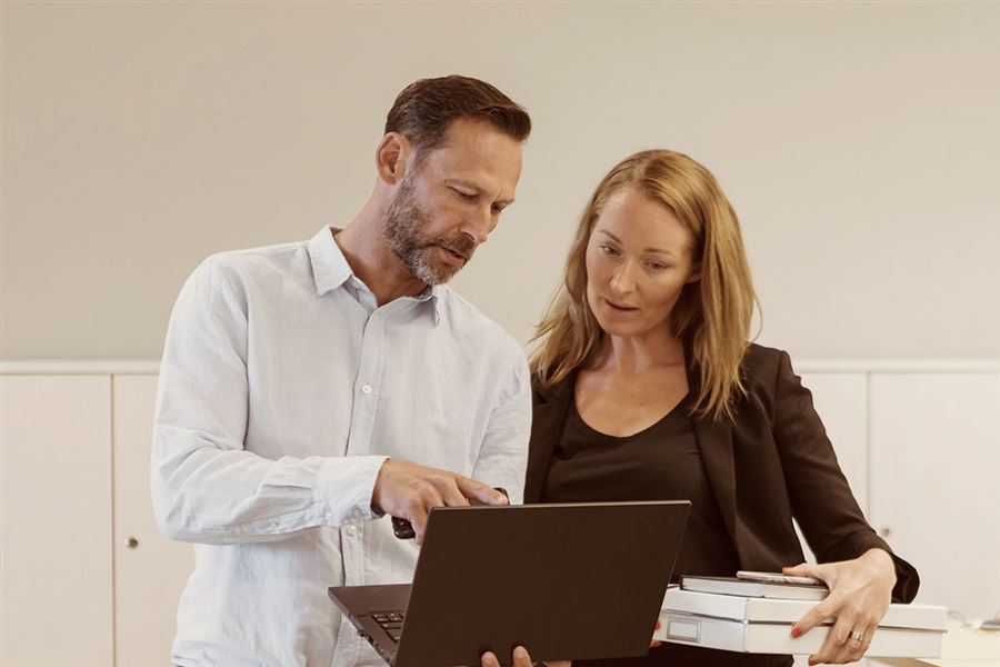 Two colleagues collaborating in front of a laptop.