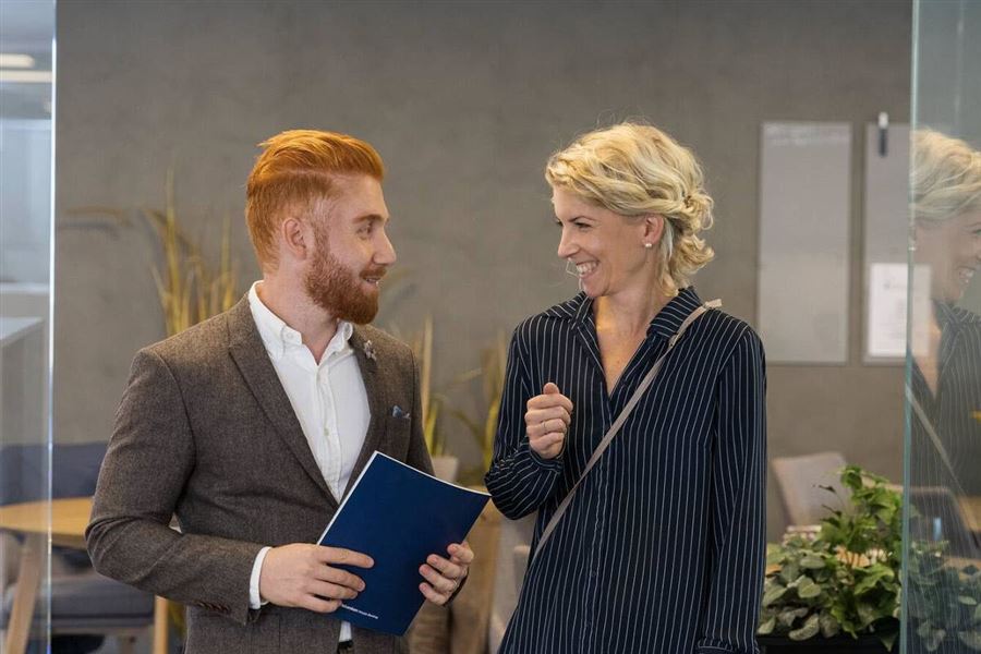 A man and a woman are talking. They are about to have a meeting in a branch office. 