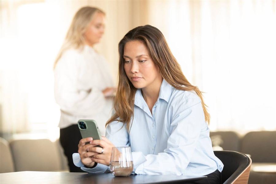 Girl at a desk looking at her phone.
